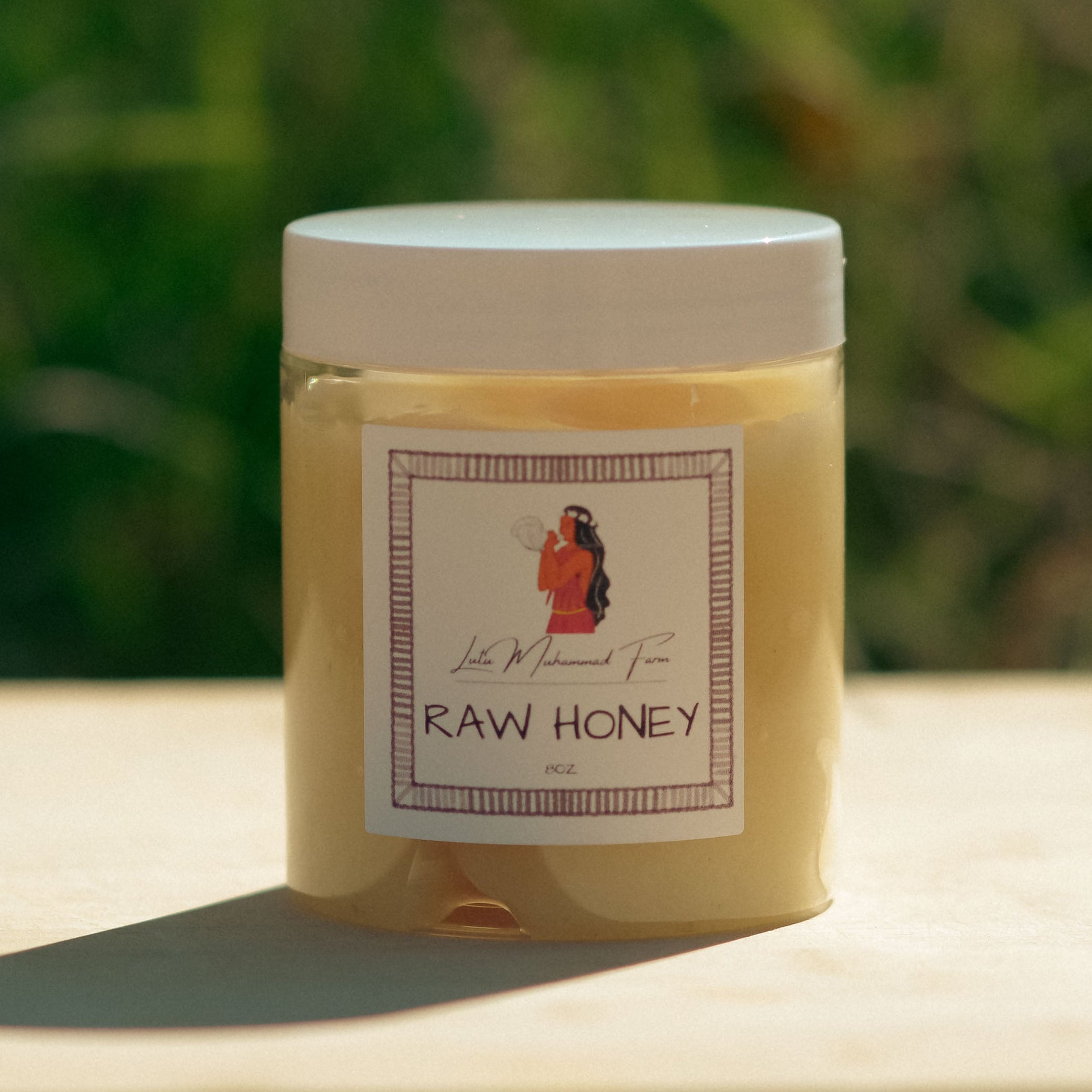 Jar of raw honey with a label on a wooden surface and blurred green background